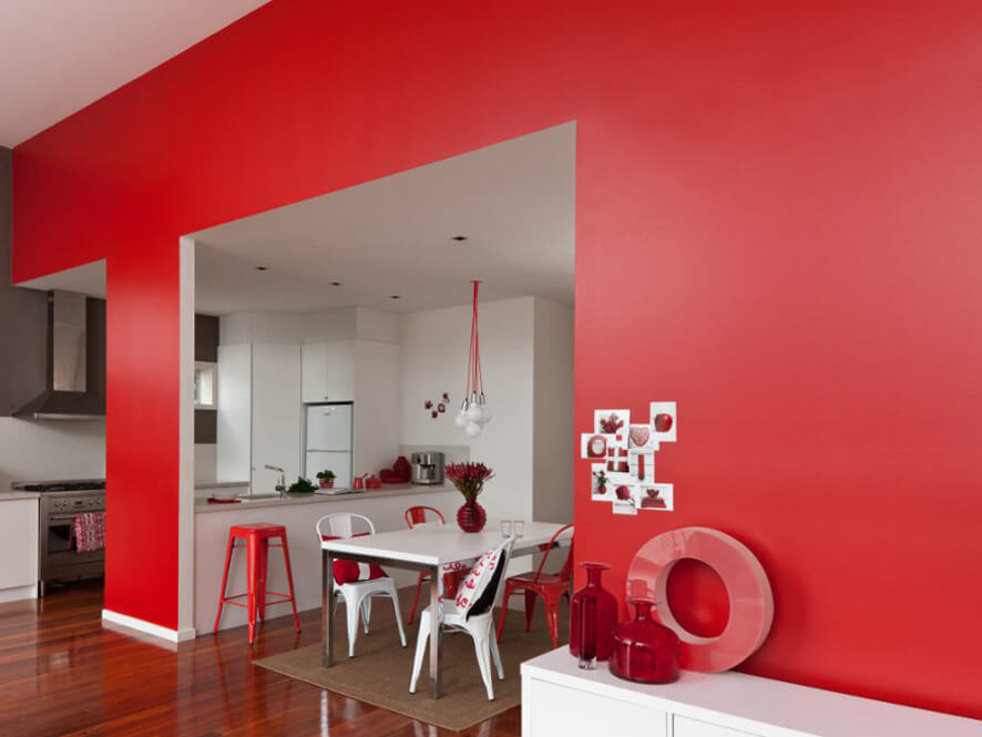 red_feature_wall_contrasting_white_kitchen_silver_appliances_deep_timber_floorboards_red_stools 